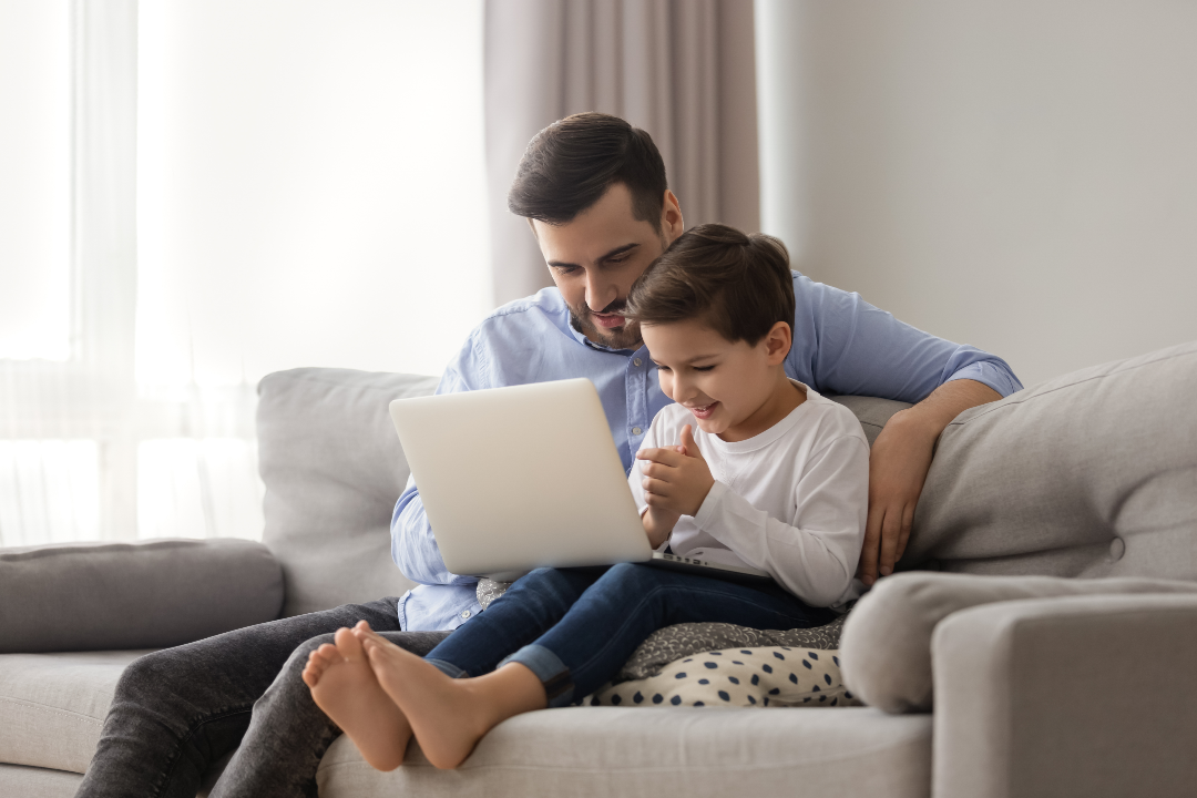 Dad and child sitting on couch with laptop